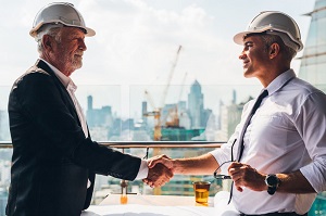 2 men shaking hands wearing hard hats