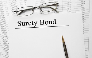 surety bonds typed on a piece of paper with glasses and a pen 